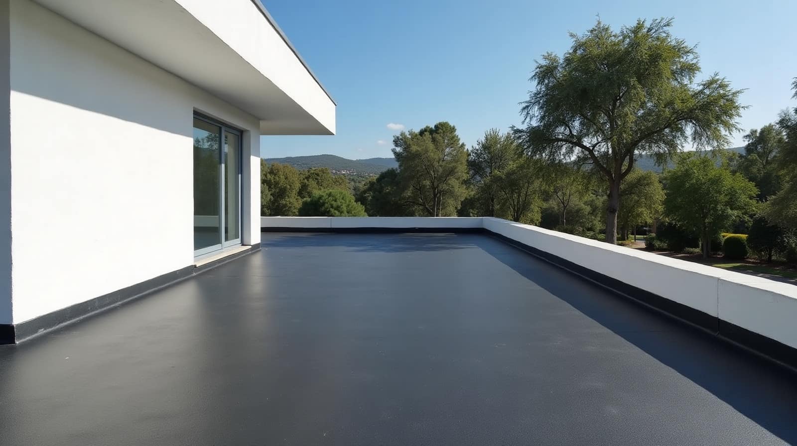 Toiture-terrasse sombre partagée entre l'ombre portée d'un mur blanc et le plein soleil, arbres de jardin au-delà